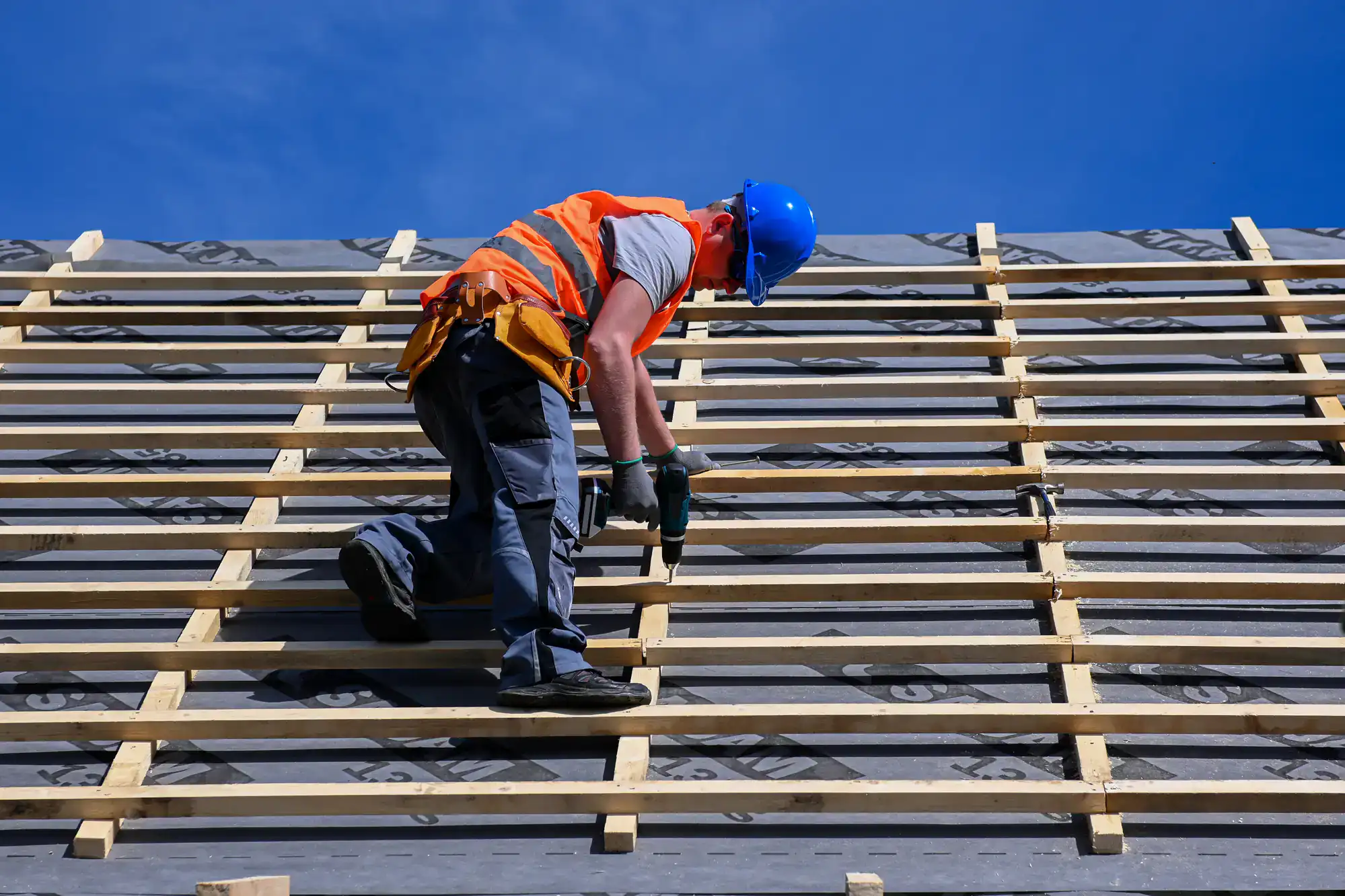 Roof framing construction with a worker installing wooden beams.